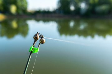 Bell on a fishing rod on the background of the river close-up. Summer fishing