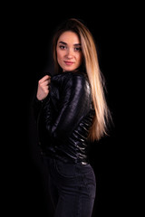 A young girl in a black leather jacket isolated on a black background
