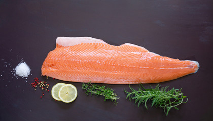 salmon fish with spices on dark background.