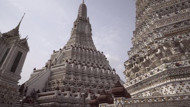Low angle panning of intricate design on Buddhist temple with tourists in city against sky during sunny day - Bangkok, Thailand