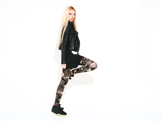 Young beautiful hipster girl in black leather jacket and stylish fashionable tight military pants leggings.Model with earring in nose.Sexy woman walking and jumping in studio.Flying hair in motion