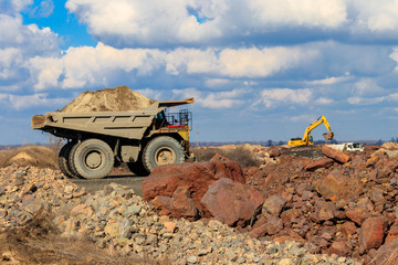 Huge yellow mining dump truck working in iron ore quarry. Mining industry © olyasolod