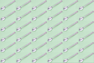 Metal dessert spoons with green background. Repeat pattern.
