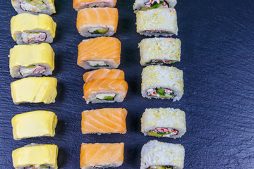 Set of sushi rolls on a black stone slate. Top view