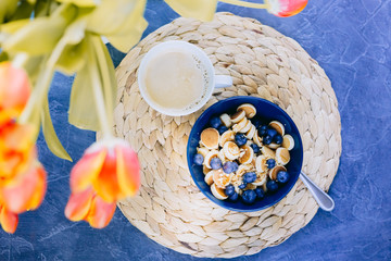 Morning, breakfast time, cereal Mini Pancake, mini pancakes in a dark blue bowl with maple sirup honey with blueberry and cup of coffee. Food background. Still life. 