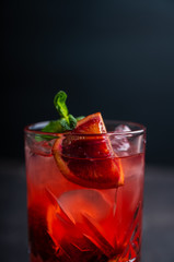 Red cocktail with blood oranges and thyme on the rustic background. Selective focus. Shallow depth of field.