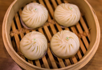 Fresh steamed traditional Chinese bao buns in a steamer basket at a restaurant in Singapore