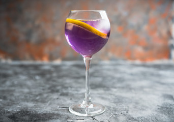 Colorful cocktail with lemon and lavender liqueur in wineglass on the rustic background. Selective focus. Shallow depth of field.
