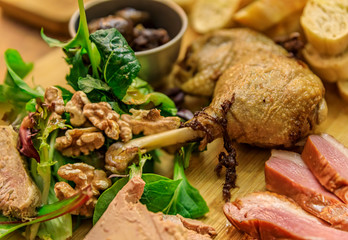 Gourmet platter with duck pate, foie gras, duck confit and seared duck breast on a wooden cutting board in a restaurant