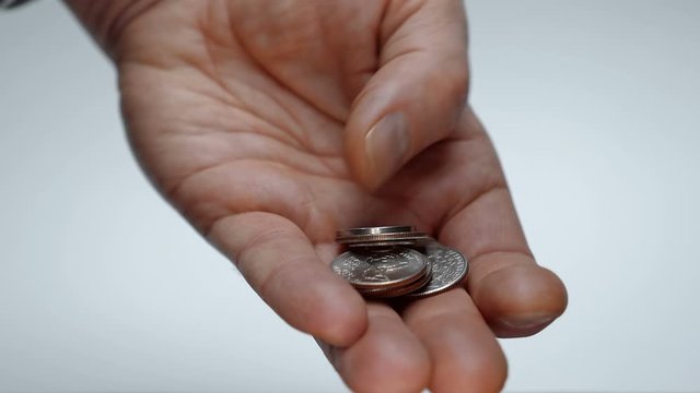 A man takes his time examining a trifle in his hand, trying to find a coin of the desired denomination. Macro. Closeup. Shallow depth of field. The camera moves around