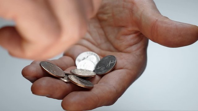 A man takes his time examining a trifle in his hand, trying to find a coin of the desired denomination. Macro. Closeup. Shallow depth of field. The camera moves around