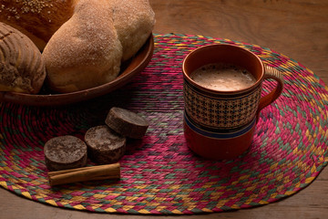 Plato de pan dulce tipico mexicano con taza de chocolate en leche en taza de barro