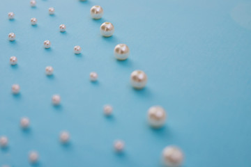 White beads lie in a row on a blue background. Needlework and embroidery. Background and texture.