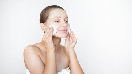 A beautiful caucasian woman cleans her skin with a facial toner using a cotton pad and smiles....
