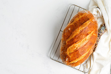 Freshy baked homemade bread on a light grey marble table decorated textile towel.