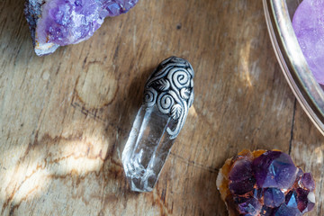 Beautiful crystal quartz gemstone pendant on wooden backround with amethyst druses