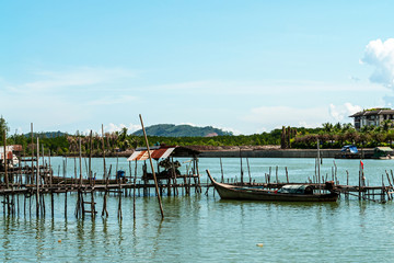 A local fisherman village standing in the water. Traditional colorful asian wooden fishing boats in village. River view with local community under the blue sky in Thailand.