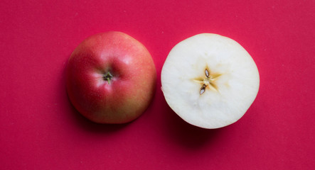 Red fresh apple cut in half on red background. Top view.