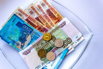 Russian rubles lying on a glass plate on a white background. Salary issue. Money.