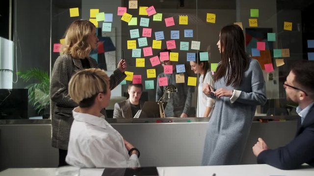 Creative Business Team Brainstorming Ideas Working Together Near Glass Wall With Sticky Notes. Colleagues approve. Business Success Concept