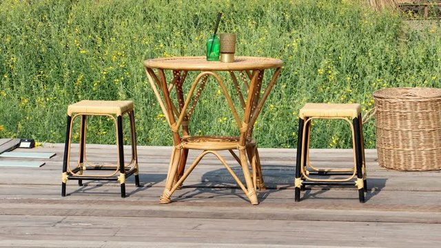 A garden sitting place against green meadow with yellow flower flying in the wind. The Handmade table with chairs on a meadow at summer day.