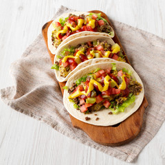 Homemade Cheeseburger Tacos on a rustic wooden board on a white wooden table, low angle view.