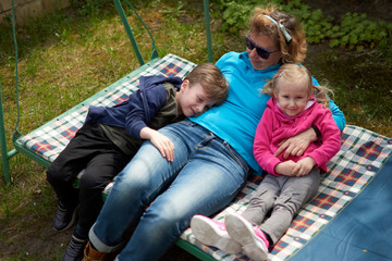 Grandmother and her two grandchildren having fun on a swing, Grandson and granddaughter relaxing...