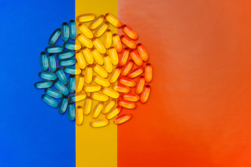 Circle of pills on a bright three colored background. Blue, Yellow and orange background. Medicine.