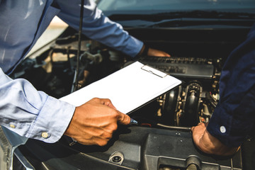 Auto mechanic using checklist for car engine systems after fixed. concepts of car insurance support...