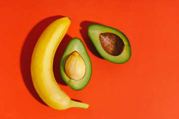 Avocado and banana on a red background. Sliced avocado. Whole banana. Bright picture