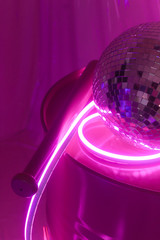 Neon light studio. Pink neon light on the baseball bat and disko ball. Colorfull reflection on the...