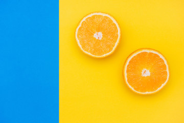 Two slices of an orange on a colorful background. Blue and yellow background