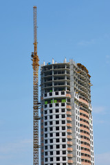 Fototapeta na wymiar Unfinished construction of high-rise building with crane.