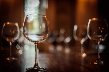 Restaurant industry related. Wine glasses on restaurant table,drink bottles and people sat at dining tables.