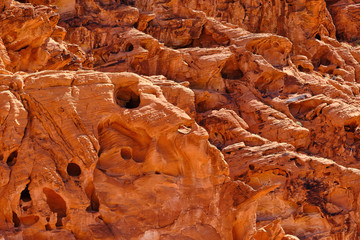 Erosion created small  holes and caves in the Red Aztec Sandstone in the Nevada Desert
