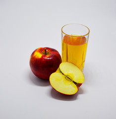 one whole red apple, half an apple and a glass of apple juice on a white background. apple source of vitamins and iron