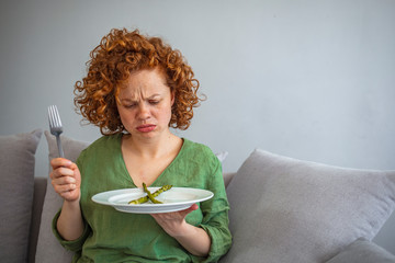 Not in the mood for diet today! Sad young woman being on diet. Redhaired woman dealing with...