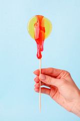 Yellow circle lollypop with droping sugar paste in hand. The concept of intimate depilation -...