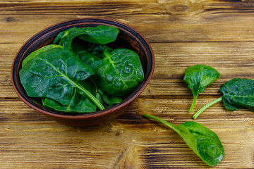 Fresh green spinach leaves in bowl on a wooden table