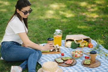 Close-up of woman hold disposable cup with coffee on picnic outdoors. Space for text. Vegan picnic concept