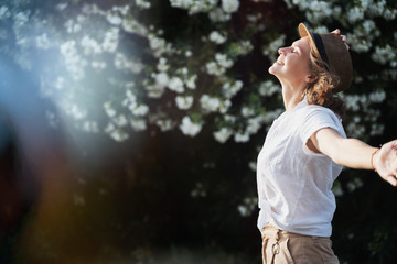 Portrait of a beautiful young stylish woman in a white shirt in a hat and sunglasses laughs...