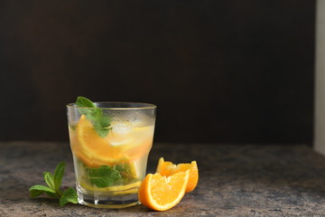 Fototapeta premium Summer drink. Cold lemonade with lemon, orange and mint on a concrete background. Horizontal focus.