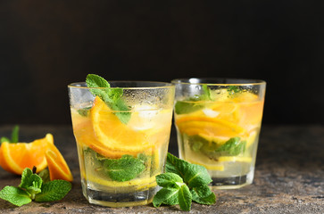 Summer drink. Cold lemonade with lemon, orange and mint on a concrete background. Horizontal focus.