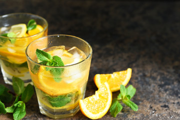 Summer drink. Cold lemonade with lemon, orange and mint on a concrete background. Horizontal focus.