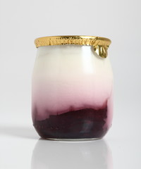 Yogurt with jam in small glass jar with aluminium foil seal cap.