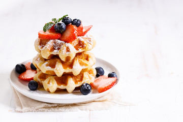 belgian waffles with fresh blueberries, strawberries and sugar.