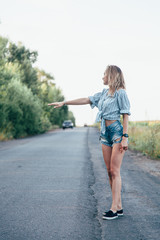 Beautiful girl hitchhiking on the track in a man's shirt