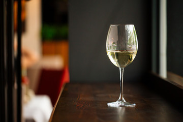 Elegant glass of white wine on wooden bar counter