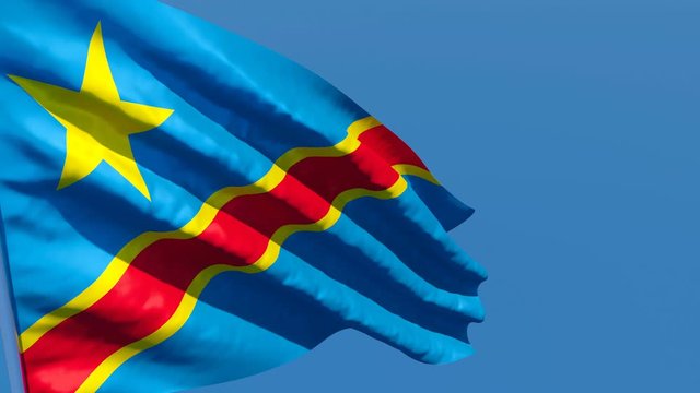 The national flag of Congo flutters in the wind against a blue sky