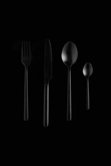 still life of black cutlery on black background, fork, knife, spoon, teaspoon 